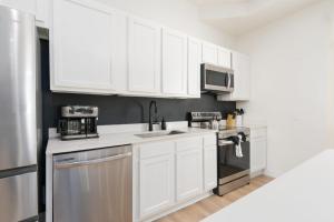 a white kitchen with white cabinets and a sink at Elegant 2 BR apt in the heart of historic SPR - 5 min drive to TIAA Bank Field in Jacksonville +22 photos