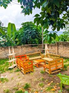 4 bancos de madera sentados junto a una pared de ladrillo en Karibu Jua Backpackers Hostel, en Mbeya