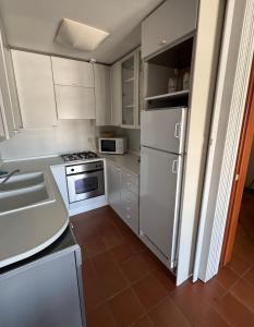 a kitchen with white cabinets and a white refrigerator at Ampio appartamento in centro con vista - terrazze, parcheggio gratuito e Wi-Fi in Lignano Sabbiadoro
