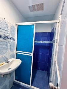 a blue bathroom with a sink and a shower at Posada Miss Gloría in San Andrés