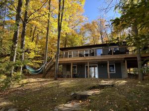 a house with a hammock in the woods at Diamond Lakehouse | SUP, Canoe, BBQ, Aurora Magic in Highland Grove