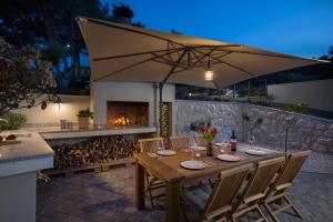 a wooden table with an umbrella and a fireplace at Olive Hill House - first floor in Slatine