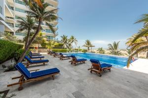 a row of blue lounge chairs next to a swimming pool at Edificio Morros Vitri, 2 Bedrooms- Comfy Apartment in Cartagena de Indias