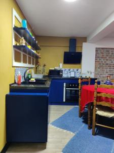 una cocina con armarios azules y una mesa roja en una habitación en OTAM Villa, en Pogradec 20 fotos más