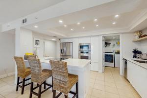 a kitchen with a white counter and chairs in it at Daytona Beach Soaring in Daytona Beach Shores