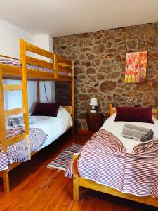 een slaapkamer met 2 stapelbedden en een stenen muur bij casa na aldeia - entre Fundão e Covilhã in Pêro Viseu