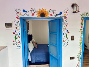 Un dormitorio con una puerta azul con un girasol en la pared. en AITANA'S HOUSE - SAN BLAs, en Cusco