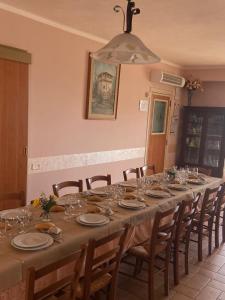 Una mesa larga con sillas, platos y copas de vino. en Agriturismo Cerquatonda, en Montalto delle Marche