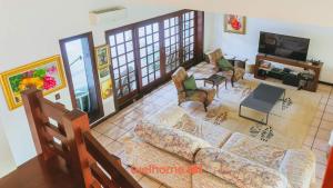 a living room with a couch and chairs and a tv at Casa de Praia no Guaruja com SPA e Piscina in Guarujá +38 photos
