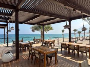 a patio with tables and chairs on the beach at The Beach House deux in Muscat