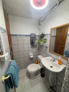 a bathroom with a toilet and a sink and a mirror at Depa Koral in Puerto Limón +64 photos