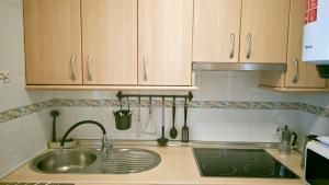 a kitchen with wooden cabinets and a sink at Apartamento Marion in Cala del Moral