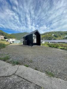 a black house sitting on top of a field at タイニーハウスTｈ01 in Higashihiroshima