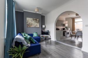 a living room with a blue couch and a kitchen at Elm View Retreat in Durham