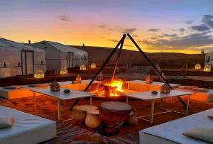 a camp with a fire and tables and tents at Private Luxury Camp in Merzouga
