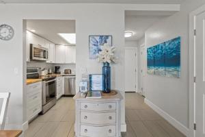a kitchen with white cabinets and a vase with flowers at KIHEI BEACH, #109 condo in Kihei +29 photos