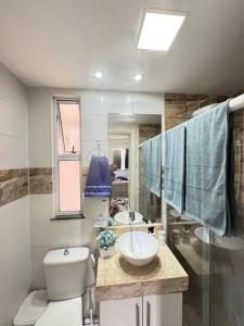 a bathroom with two sinks and a toilet and a mirror at Apto completo com ar, piscina 2 quartos in Camaçari