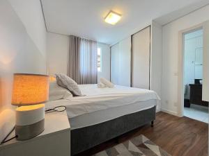 une chambre avec un lit et une table avec une lampe dans l'établissement Residencial Porto Piçarras - Itacolomi, à Balneário Piçarras 20 autres photos