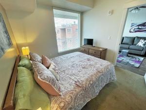 a bedroom with a bed and a window with a couch at Luxury Condo in the Library Square District in Salt Lake City