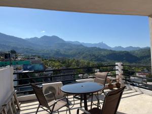 a balcony with a table and chairs and mountains at verde amanecer in Xilitla