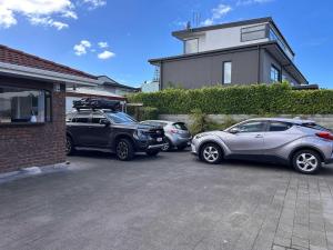 three cars parked in a parking lot in front of a house at A Hidden Gem in Auckland