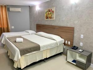 a hotel room with two beds and a table at HANNA Arcos d'Atalaia Hotel - Aracaju in Aracaju