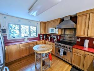 una cucina con mobili in legno e un tavolo al suo interno di Oceanfront Crackling Cove Cottage Family firer pit slleeps 6 a Gouldsboro