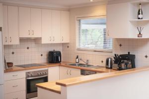 a kitchen with white cabinets and a sink at A Coastal Break in Inverloch