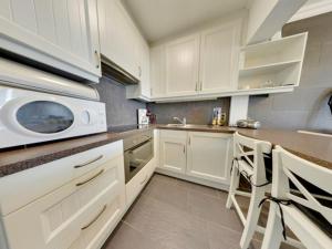 a kitchen with white cabinets and a microwave at Studio in Middelkerke with Sea View in Middelkerke