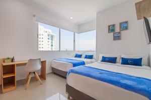 a bedroom with two beds and a desk and window at Vista de lujo al mar y la bahía in Cartagena de Indias +25 photos