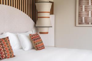a bed with a lamp and a pillow on it at Kimpton Atlantico Algarve by IHG in Albufeira