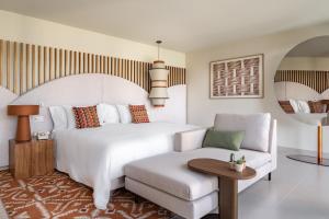 a bedroom with a large white bed and a chair at Kimpton Atlantico Algarve by IHG in Albufeira