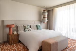 a bedroom with a large white bed and a large window at Kimpton Atlantico Algarve by IHG in Albufeira