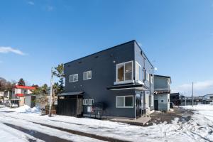 a black house on a street in the snow at スプリングヒルズ高田屋 in Hakodate