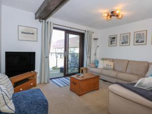 a living room with a couch and a tv at Hafan Bach - 233 Cae Du in Abersoch