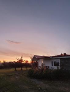 a white house with a sunset in the background at Cabañas Patagonia Encantada in Puerto Natales