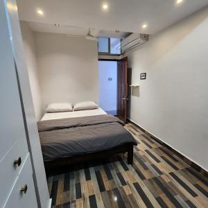 a small bedroom with a bed and a wooden floor at Stylish comfy Room near Airport in Chennai