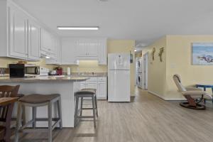 a kitchen with white cabinets and bar stools at Boardwalk Shores C Duplex in Atlantic Beach