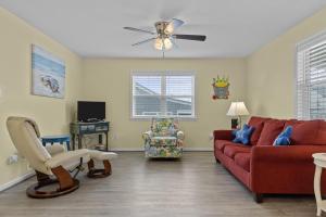 a living room with a red couch and a chair at Boardwalk Shores C Duplex in Atlantic Beach