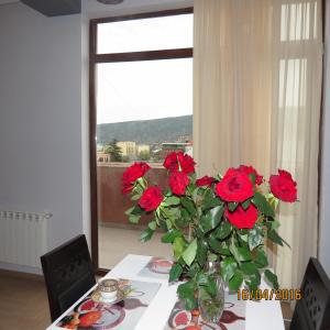 un vase rempli de roses rouges assis sur une table dans l'établissement Apartment With Terrace in Avlabari, à Tbilissi
