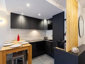 una cucina con armadi neri e tavolo in legno di Duplex rénové 6 pers avec vue sur lac à Loudenvielle - FR-1-695-72 a Loudenvielle