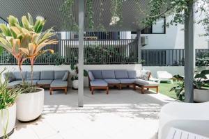 a patio with couches and plants in a building at Coolum Gem with BBQ & Stunning Pool in Coolum Beach