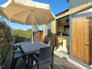 Tiny House 1 chambre, piscine chauffée, à 200 m de la plage, Jullouville - FR-1-361A-24 في جولوفيل ليه باه: طاولة وكراسي مع مظلة على السطح