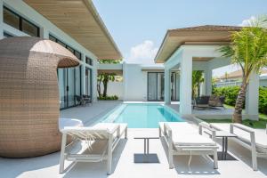 a villa with a swimming pool and a resort at Mouana Breeze Mai Khao VIP 4-bedroom Pool Villa 9913 in Mai Khao Beach