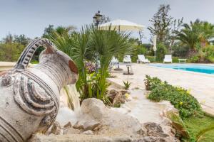 a water feature in a garden next to a swimming pool at B&B Tenuta Martinelli in Monopoli