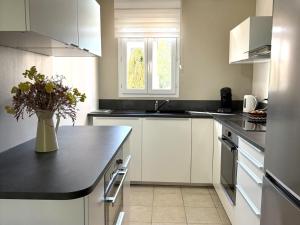 a kitchen with white cabinets and a vase of flowers on a counter at Maison Calme 6 Pers. au Golf Pont Royal - Piscine, Terrasse, Parking, Clim, Fibre - 13370 Mallemort - FR-1-658-24 in Mallemort