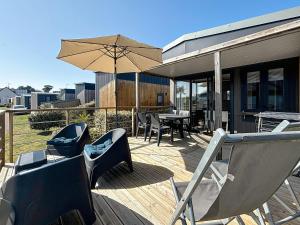 a patio with chairs and a table and an umbrella at Mobil-home Confort 4 pers, plage à 200m, piscine chauffée, terrasse Sud, parking, wifi inclus - FR-1-361A-81 in Jullouville-les-Pins