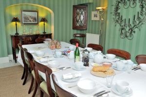 uma sala de jantar com uma mesa com pratos brancos em B&B Castleton House em Mere