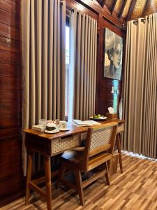 a wooden desk with a chair and a table and curtains at Balikaru Living in Penebel