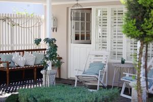 a porch with two chairs and a table and a door at Kastelein Guesthouse in Pongola